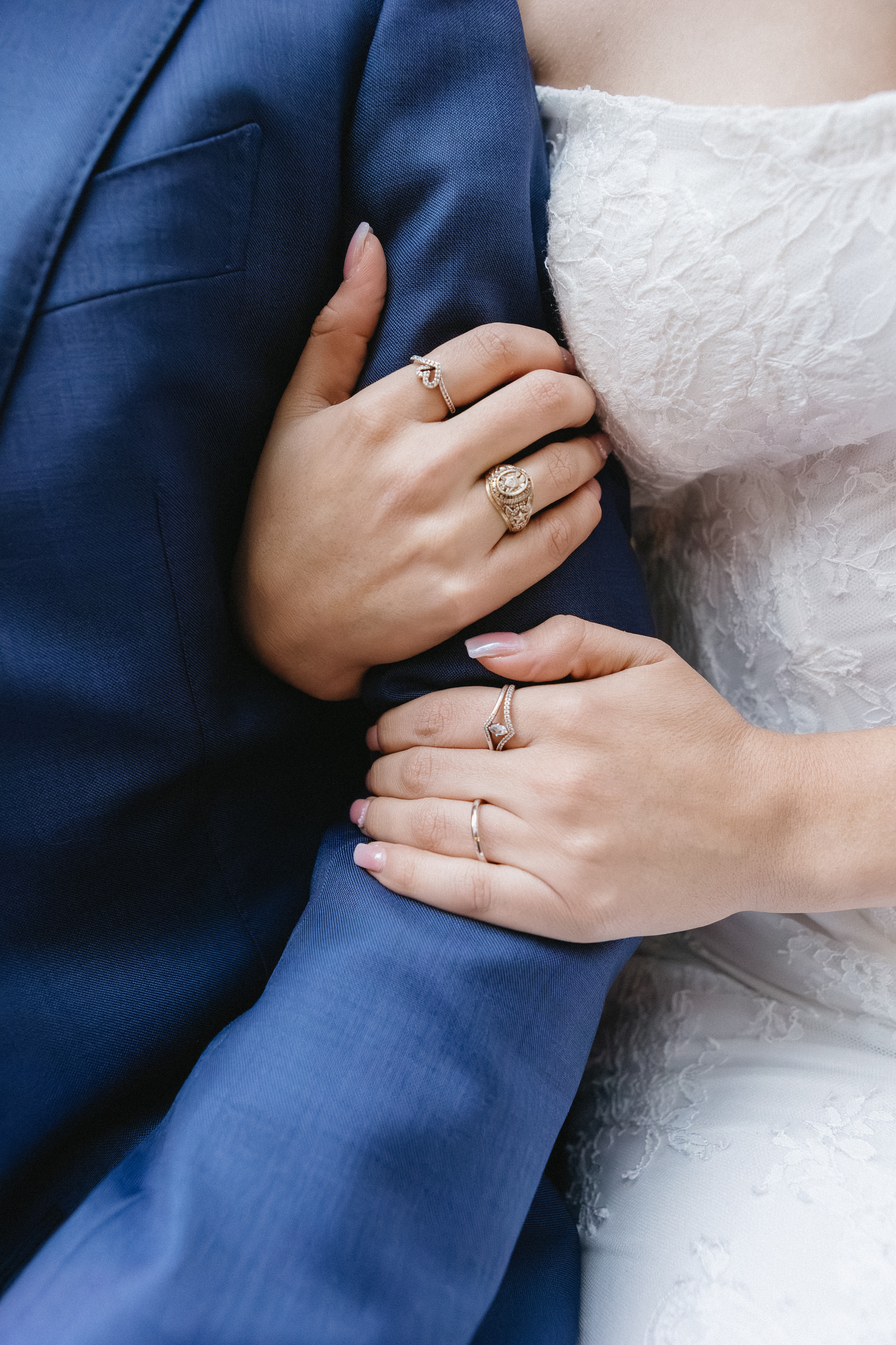Bride's hands resting on a groom's blue suit