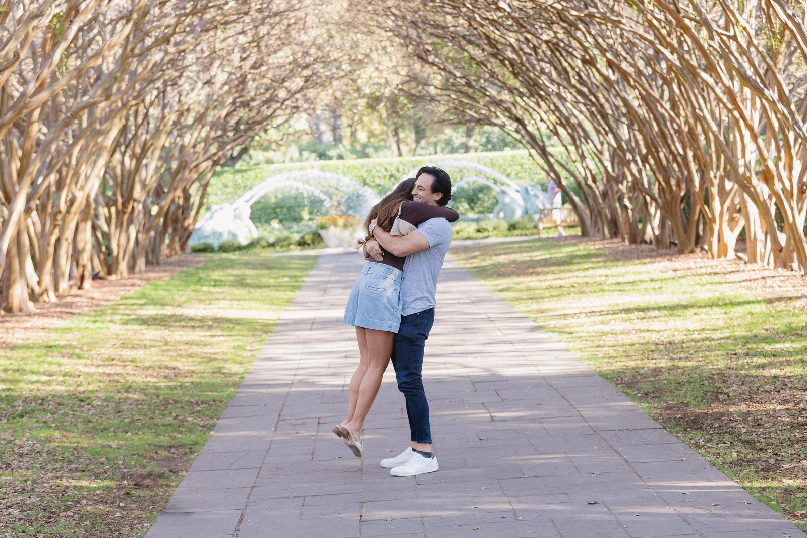 Couple embracing beneath an archway of trees